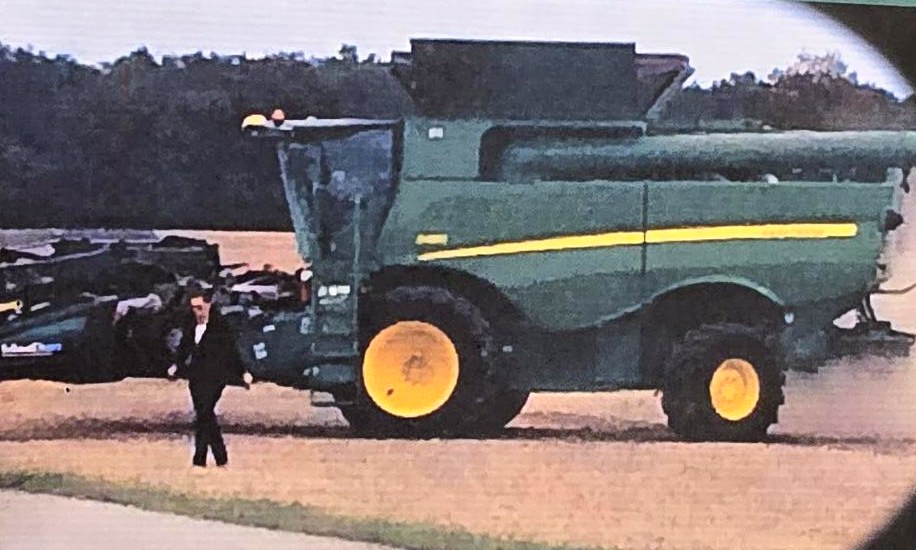 Sarah Dimmich in a black suit walking away from a green combine in a field